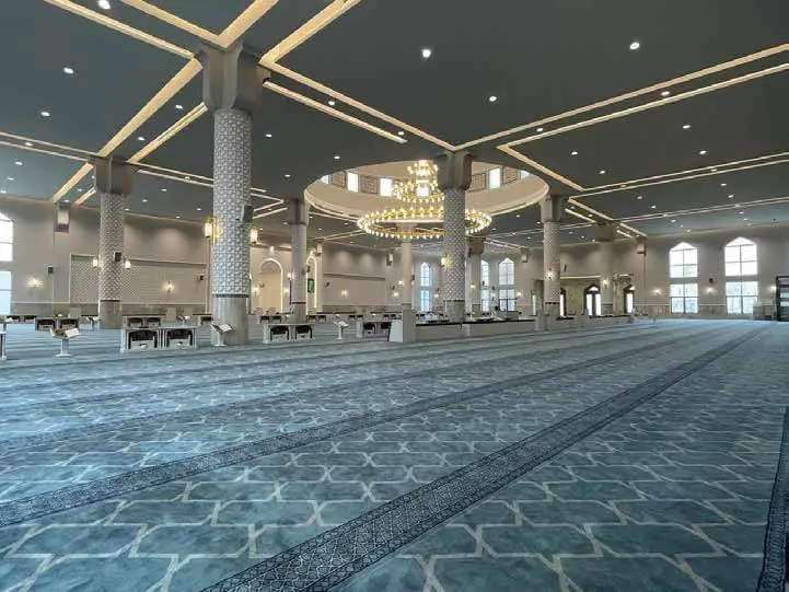 مصلى بسجاد أزرق فاتح بنقوش هندسية وأعمدة وثريا في الوسط