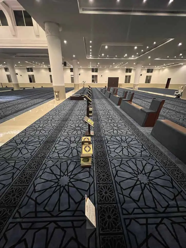 ممر بين صفوف السجاد الرمادي ورفوف المصاحف